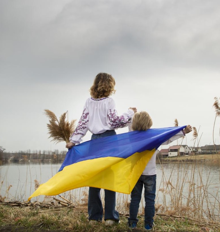 Gyerekek ukrán zászlóval a tóparton.