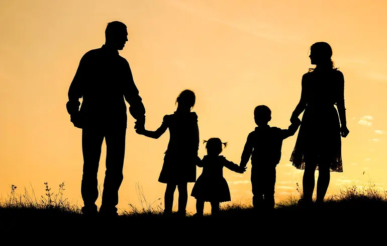 Öttagú család sziluettje naplementében kézen fogva