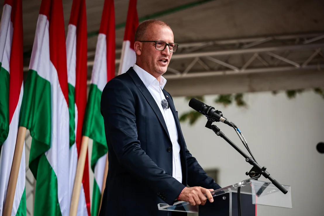 Férfi beszédet mond magyar zászlók előtt