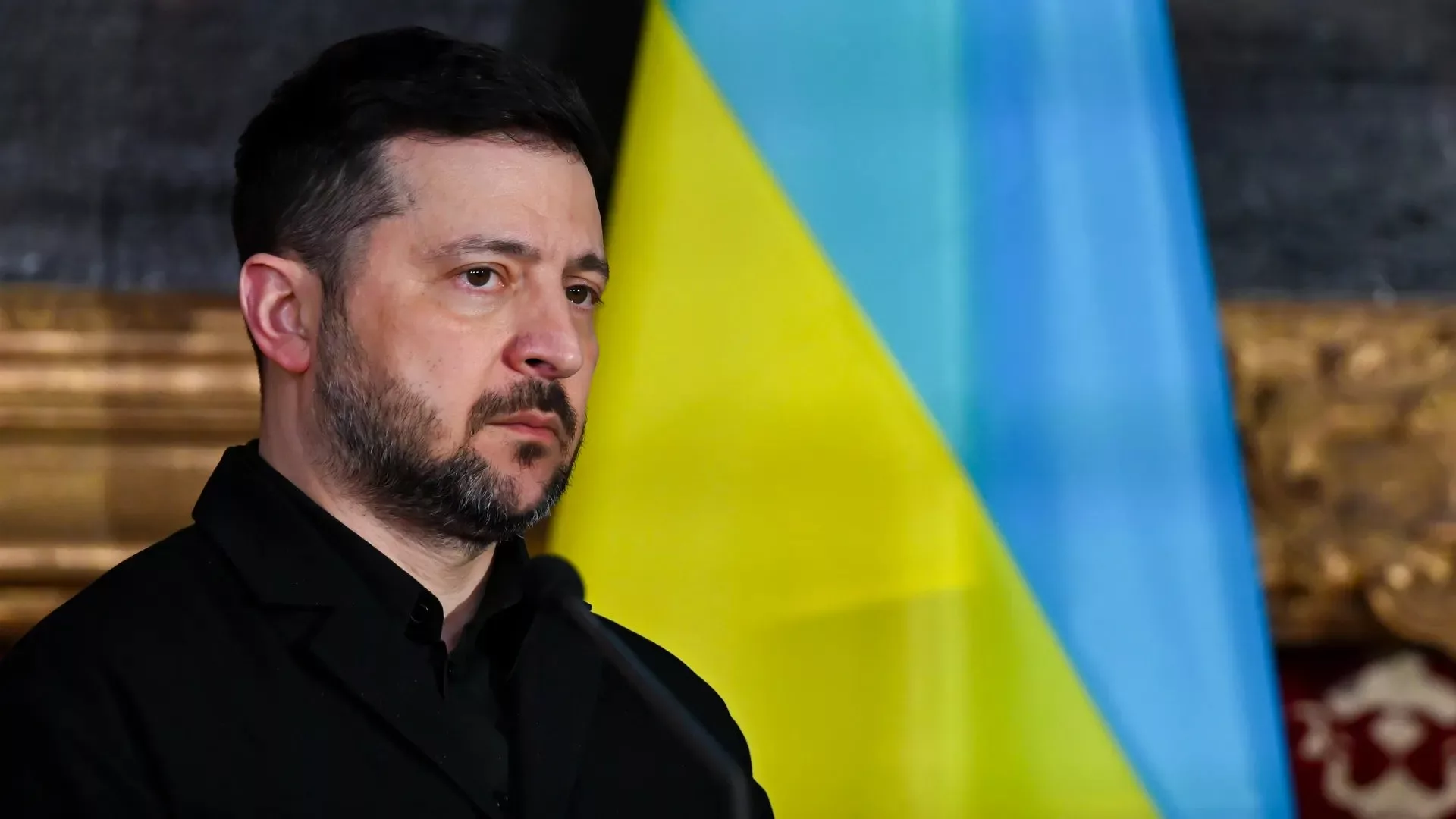 Férfi beszél az ukrán zászló előtt