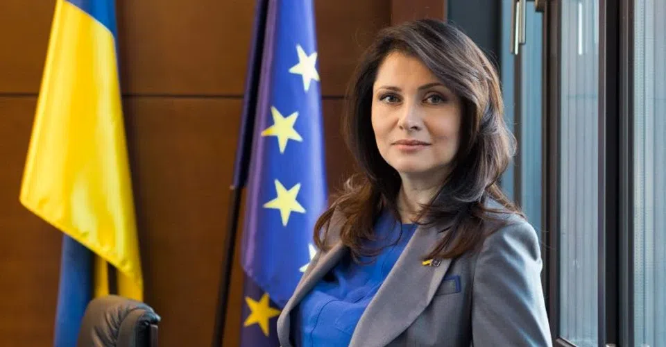 Üzleti öltözetű nő ukrán és EU zászlókkal