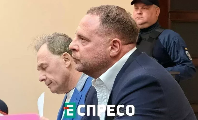 Két férfi tárgyalóteremben, biztonsági őr háttérben
