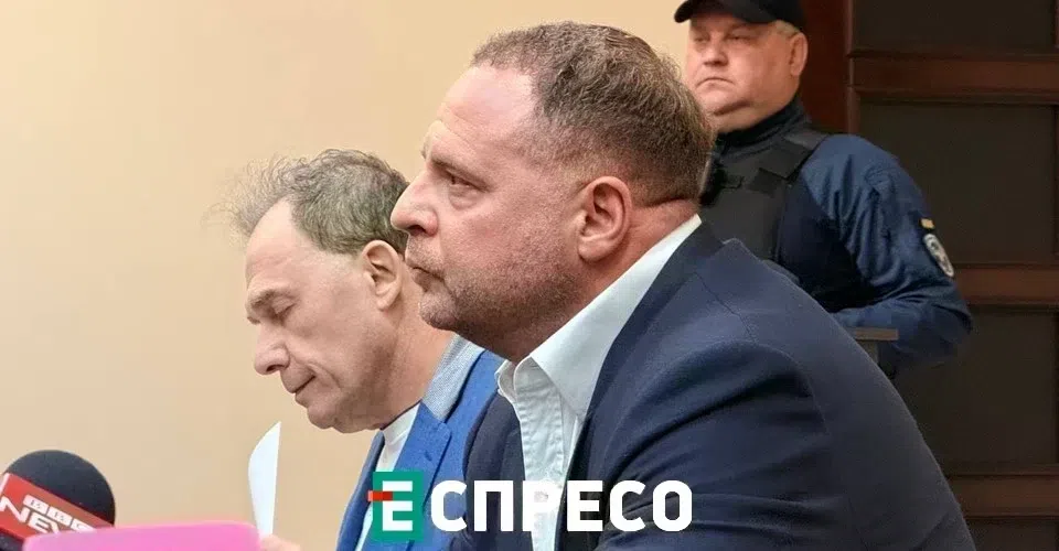 Két férfi tárgyalóteremben, biztonsági őr háttérben