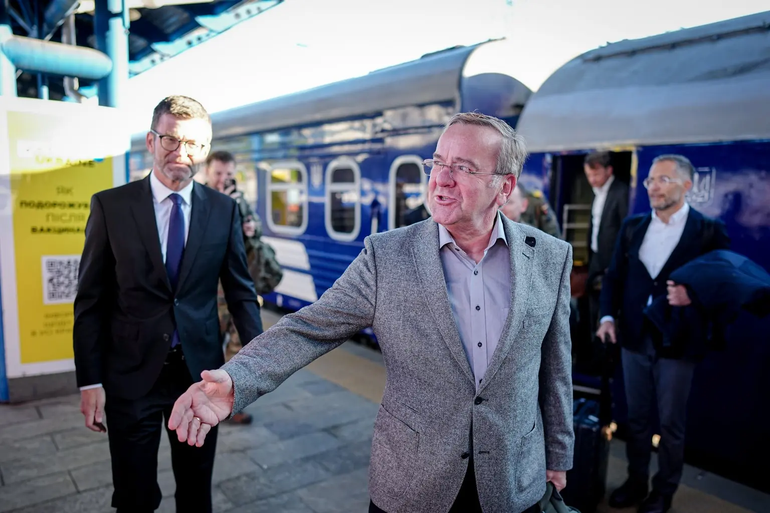 Öltönyös férfiak vonat mellett kézfogásra készülnek