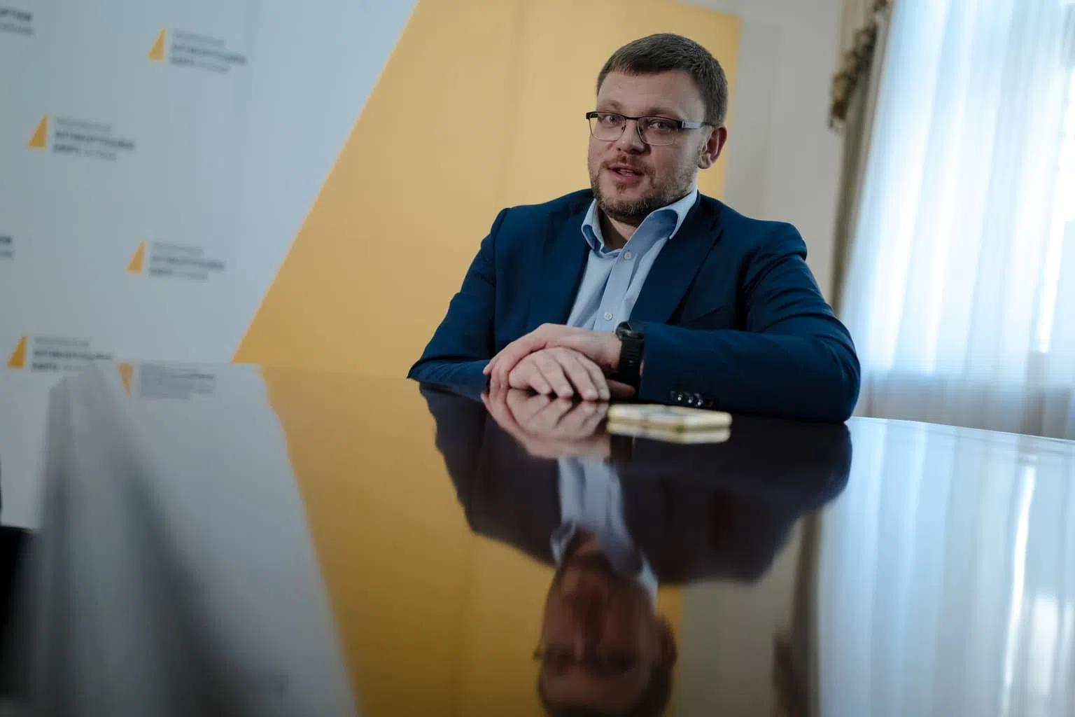 Öltönyös férfi asztalnál irodai környezetben