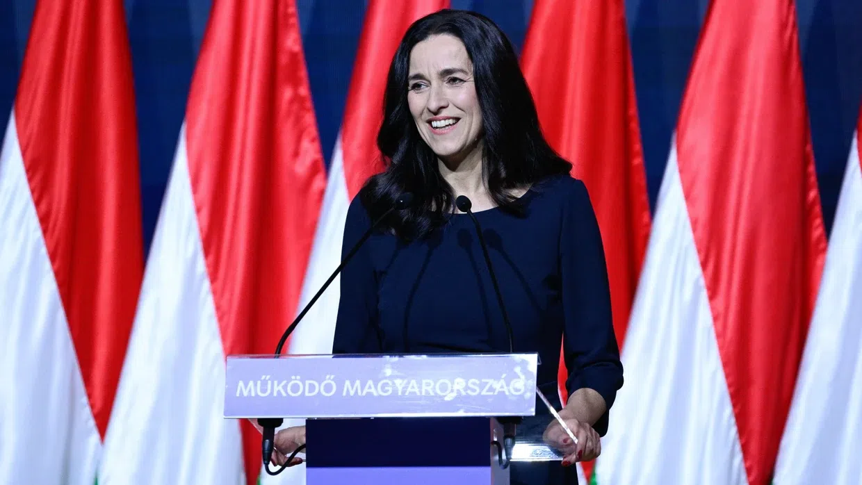 Nő beszédet mond magyar zászlók előtt