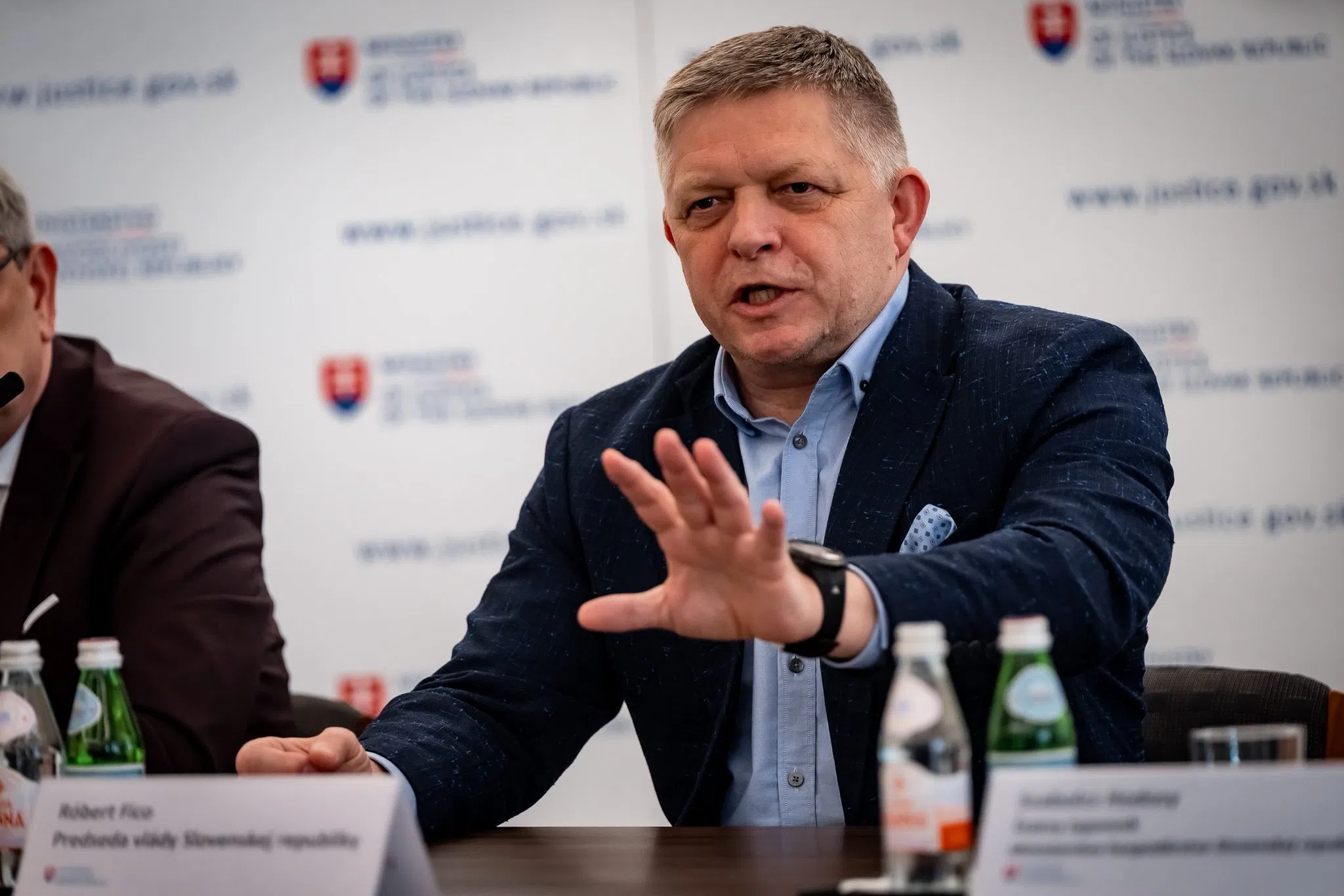 Férfi sajtótájékoztatón beszél, kezével gesztikulál