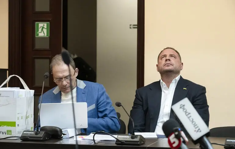 Két férfi tárgyalóasztalnál, mikrofonokkal