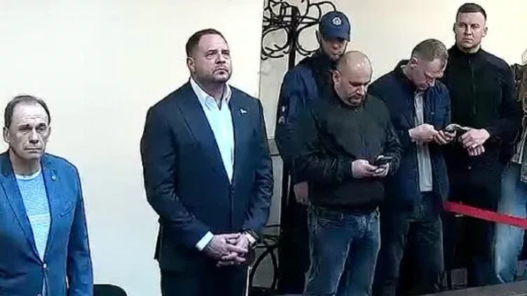 Férfiak egy teremben, némelyik telefonját nézi