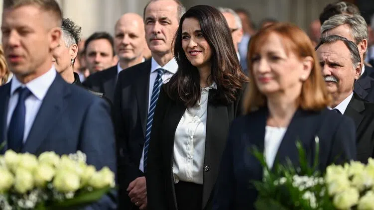 Elegánsan öltözött emberek fehér virágokkal egy ünnepségen