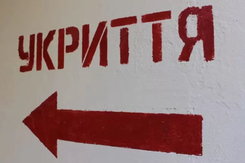 Piros ukrán 'УКРИТТЯ' felirat balra mutató nyíllal