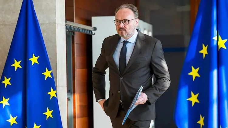 Öltönyös férfi EU zászlók között mappával